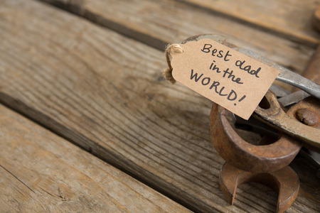 High angle view of greetings with rusty work tools on wooden table