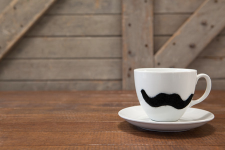 Close up of coffee cup with mustache on wooden tableの写真素材