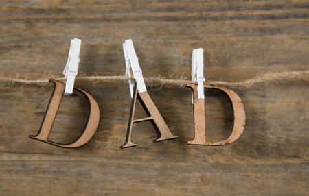 Close up of dad text hanging on string against wooden wallの写真素材