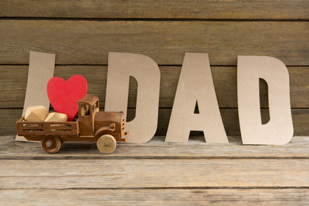 Close up of dad text by heart shape in toy truck on wooden tableの写真素材