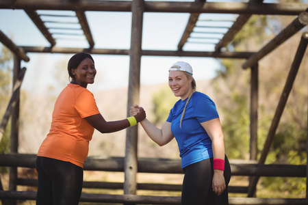 Portrait of happy friend holding hands during obstacle course in boot campの写真素材