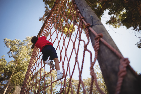 Boy climbing a net during obstacle course in campの写真素材
