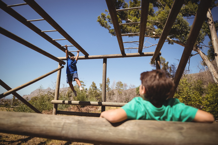 Boys exercising on monkey bar during obstacle course in boot campの写真素材