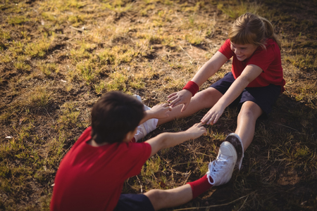 Happy kids performing stretching exercise during obstacle course in boot campの写真素材