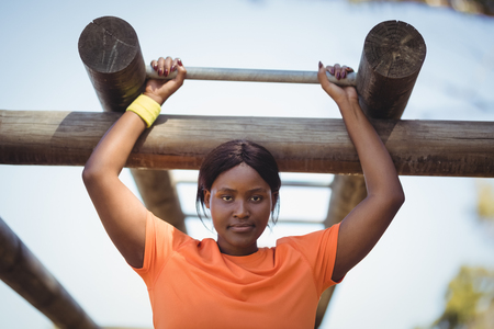 Determined woman exercising on monkey bar during obstacle course in boot camp