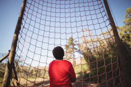 Rear view of kid looking at net during obstacle course in boot campの写真素材
