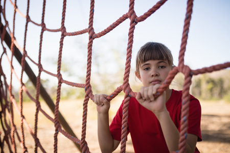 Portrait of girl standing near net during obstacle course in boot campの写真素材