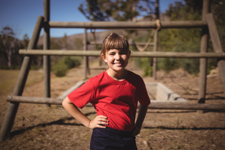 Portrait of happy girl standing with hands on hip during obstacle course in boot campの写真素材