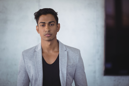 Portrait of young businessman standing against wall at officeの写真素材