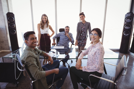 Portrait of businessman with young creative team at office deskの写真素材