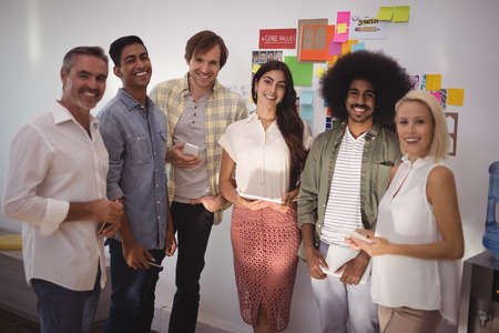 Portrait of smiling business people standing in creative office