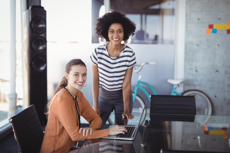Portrait of businesswomen with laptop in creative officeの写真素材