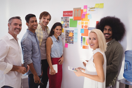 Group of smiling business people standing by wall in creative officeの写真素材