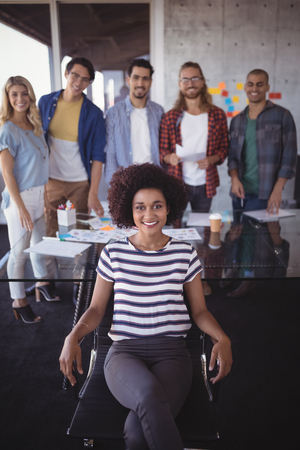 Portrait of confident businesswoman with creative team in officeの写真素材