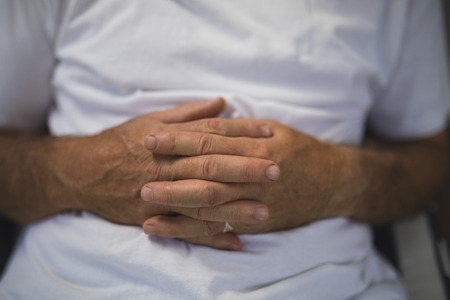 Mid section of senior man with hands clasped