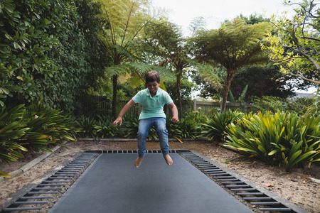 Full length of happy boy jumping on trampoline at park