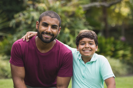 Portrait of smiling father and son sitting at parkの写真素材