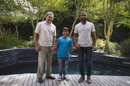 Portrait of smiling multi-generation family holding hands while standing at porch