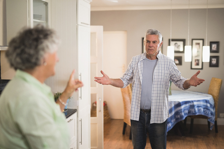 Angry senior man looking at female partner in living roomの写真素材