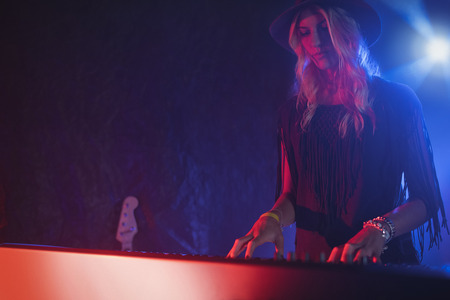 Confident female performer playing piano in illuminated nightclubの写真素材