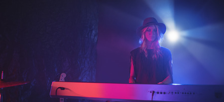 Low angle view of female performer playing piano in illuminated nightclubの写真素材