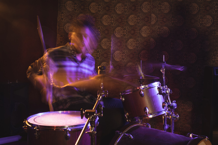 Blurred motion of male drummer performing in nightclubの写真素材