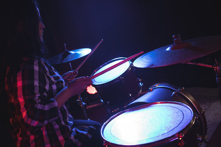 Side view of female drummer practicing in nightclubの写真素材
