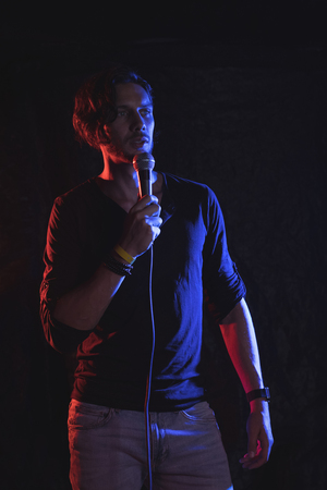 Confident male singer performing in illuminated nightclubの写真素材