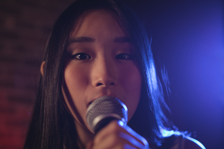 Close up portrait of female singer singing at music concert