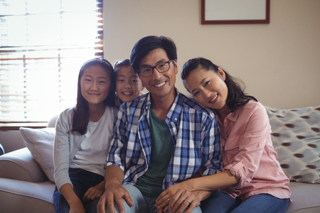Portrait of smiling family relaxing on sofa in living room at homeの写真素材