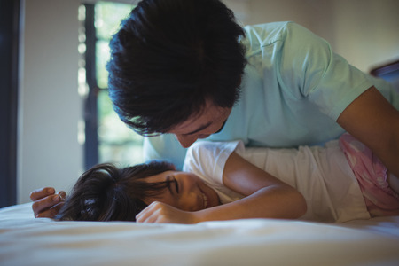 Father and daughter having fun on bed in bed room at homeの写真素材