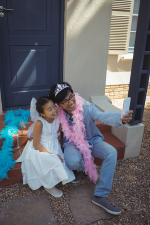 Father and daughter in fairy costume taking a selfie at homeの写真素材