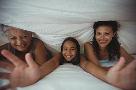 Portrait of happy family lying on bed in bed room at homeの写真素材