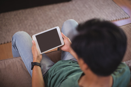 Man using digital tablet in living room at home