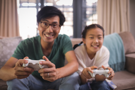Father and daughter playing video game in living room at home