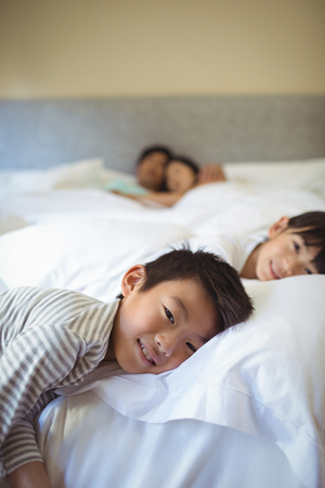 Siblings sleeping on bed in bedroom at homeの写真素材