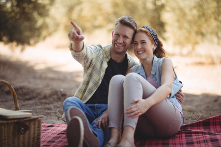 Smiling young man showing something to woman while sitting at olive farmの写真素材