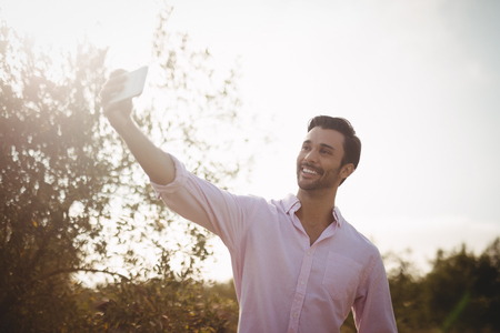 Low angle view of smiling young man taking selfie on dayの写真素材