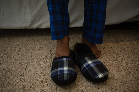 Low section of man by shoe on floor at homeの写真素材