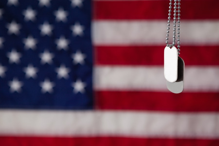 Close-up of dog tag hanging against American flag backgroundの写真素材