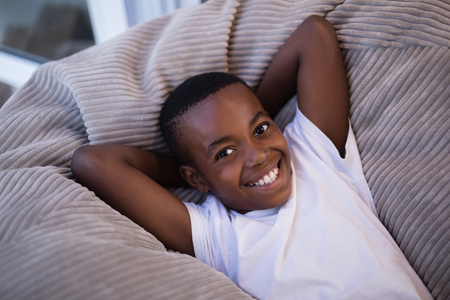 High angle view of smiling boy resting on couch at homeの写真素材