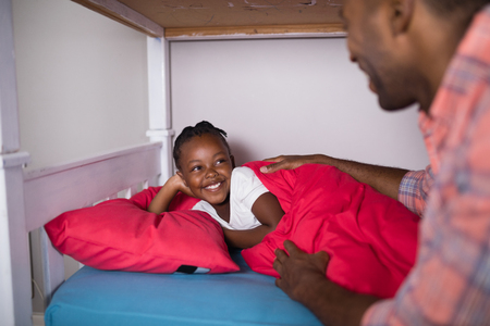 Cropped image of father talking to daughter lying on bed at homeの写真素材