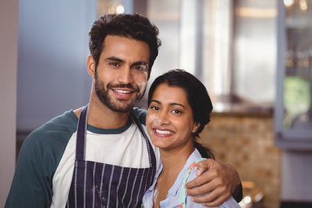 Portrait of smiling young couple embracing in kitchen at homeの写真素材