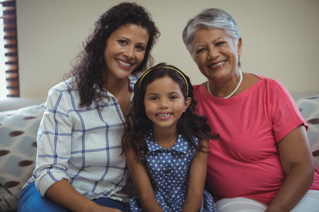 Portrait of happy family sitting on sofa in living room at home