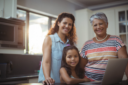 Portrait of happy family using laptop in kitchen at home