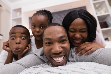 Portrait of happy family lying together on bed at homeの写真素材