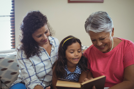 Mother and daughter reading book in living room at home