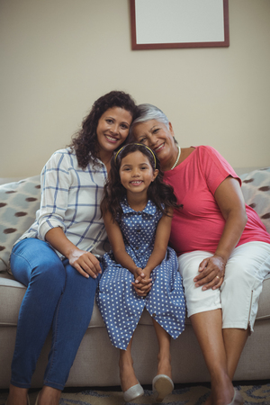 Portrait of happy family sitting on sofa in living room at homeの写真素材