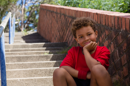 Portrait of boy sitting on staircase in the boot camp on a sunny dayの写真素材