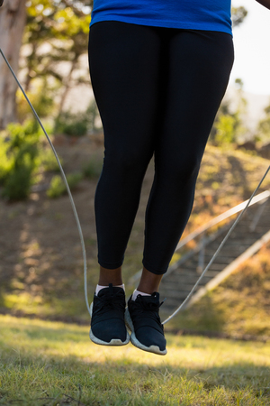 Low-section of woman skipping rope in the park on a sunny dayの写真素材